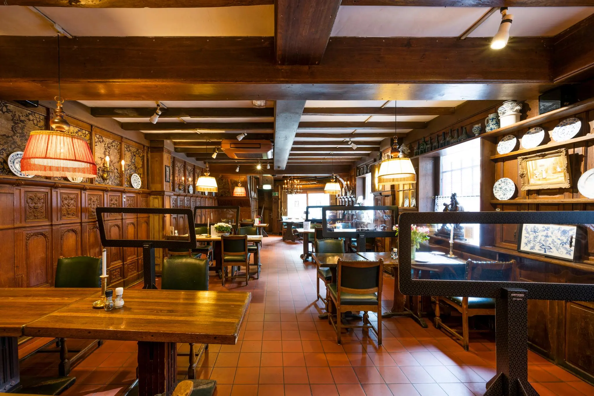 Authentiek ingericht restaurant aan de Nieuwezijds Voorburgwal met houten lambrisering, antieke decoraties en gedekte tafels.